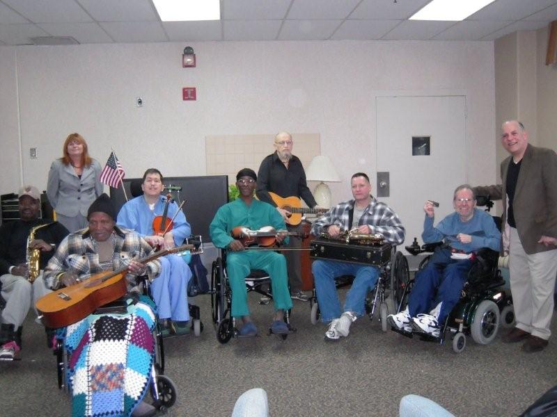 Lou Tansky poses with veterans at the Louis Stokes Medical center. The Veterans hold guitars and other instruments that will be used for music therapy sessions.