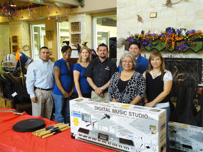 A group of Gift Day donors stand with a large keyboard and other instruments they have donated.