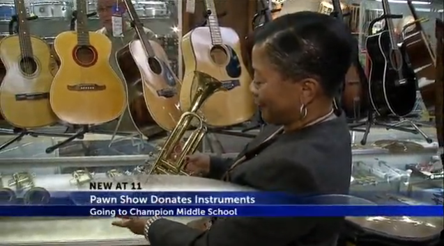 Rep. of Champion Middle School holding a donated trumpet at Uncle Sam's Pawn Shop